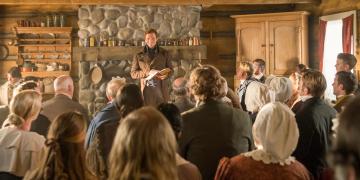 Joseph Smith stands in front of a crowd of people in the Whitmer home in this still from “A Day for the Eternities,” a film produced by The Church of Jesus Christ of Latter-day Saints.